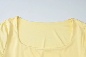 Détail de l'encolure carrée et de la texture côtelée d'une robe jaune à manches longues