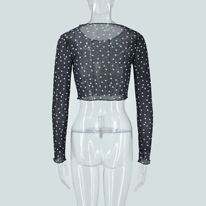 Back view of a cropped black mesh top with white polka dots and lettuce trim edges