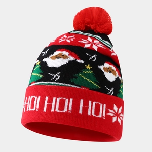 Close-up of knit Christmas hat with festive Santa Claus patterns and white pom pom detail