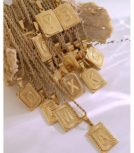Dettaglio dei ciondoli con iniziali placcati in oro 18K su piastrine rettangolari