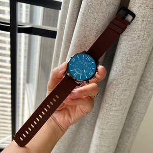 Men's blue dial quartz watch with brown rubber strap and black metal case on wrist