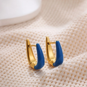 Macro shot of U-shaped earrings with blue enamel finish and gold plating on knit texture