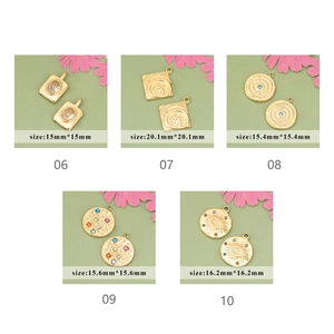 Macro view of geometric stainless steel gold charms with starburst and eye engravings