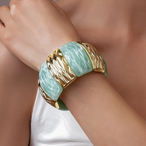 Detail of wide mint green resin and gold wavy metal textured segments on a stretch bracelet