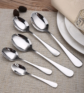 Five-piece stainless steel spoon set on a woven placemat with a natural dining setup