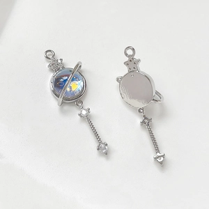 Macro detail of 14k gold planet pendant with zircon inlay and star charm on white surface
