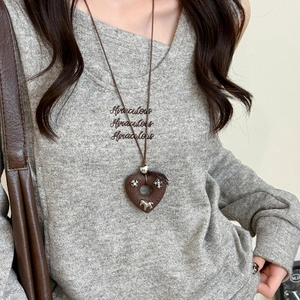 Close-up of heart-shaped leather pendant with metal horse inlay on long brown cord