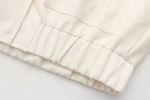 Vue détaillée du blouson aviateur blanc cassé montrant la texture sergé et l'ourlet
