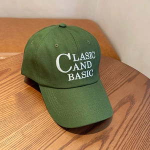 Detail shot of forest green cotton baseball cap with white CLASIC AND BASIC embroidery