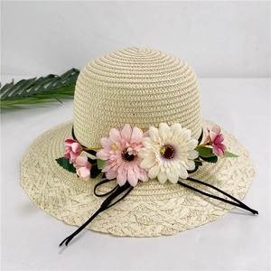 Detail of beige woven straw sun hat with large floral decorations and black ribbon