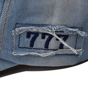 Macro del ricamo 777 su berretto di jeans azzurro con bordi consumati effetto vintage