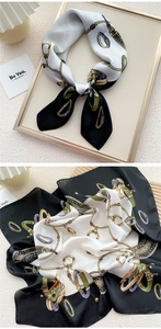 Detail of silk-like square scarf with gold chain and buckle patterns on beige background