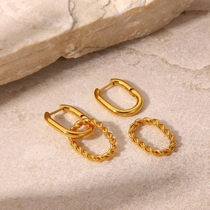 Golden twisted rope pendant earrings with U-shaped hoops on natural stone background