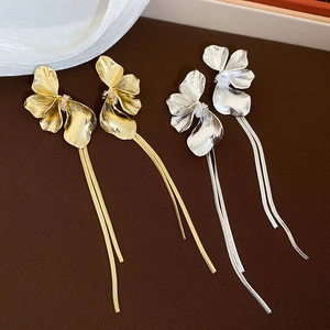 Détail de boucles d'oreilles pétales en métal avec zircons en doré et argenté