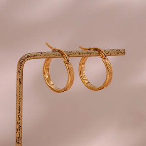 Macro detail of 20mm gold-plated hoop earrings featuring diagonal striped texture