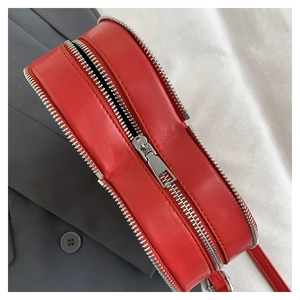 Detailed view of red leather handbag featuring premium silver metal zipper and fine texture
