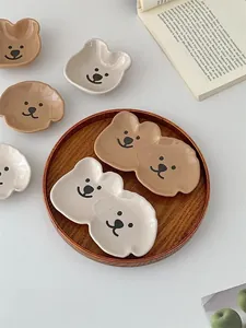 Detail of cute bear ceramic dipping saucers and double snack plates on a wooden tray