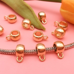 Close-up of rose gold plated bail beads and charms on a silver chain with floral decor