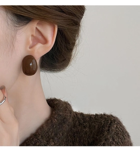 Gros plan d'une boucle d'oreille ovale en résine marron portée par un mannequin