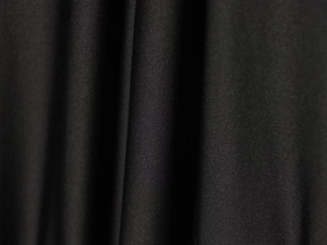 Close-up of black knitted dress fabric showing elastic weave texture and drape detail