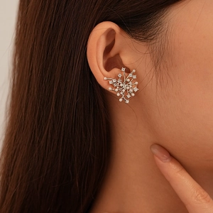 Detailed view of silver snowflake earrings with white pearls and zircons on a model's ear