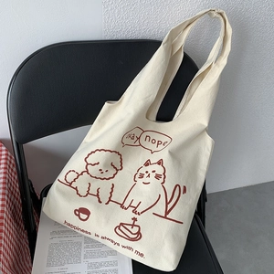 Detail of canvas tote bag with cat and dog illustrations on a black chair