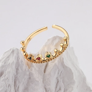 Macro shot of gold-plated crown ring with colorful cubic zirconia on white stone