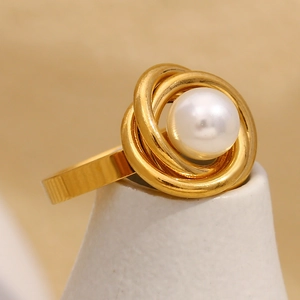 Détail d'une bague enveloppante dorée ornée d'une perle blanche ronde et brillante