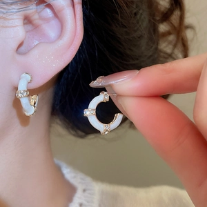 Detail view of bamboo-shaped C-hoop earrings with white enamel and sparkling zircon