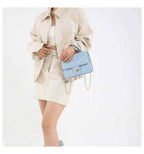 Détail du sac matelassé bleu clair avec chaîne dorée porté par un mannequin