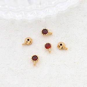 Detail of five 18k gold plated round red zircon pendants for DIY jewelry making