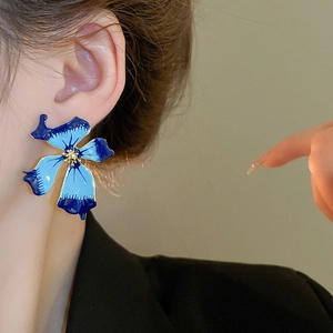 Gros plan sur les boucles d'oreilles fleurs en émail bleu avec dégradé et dorure