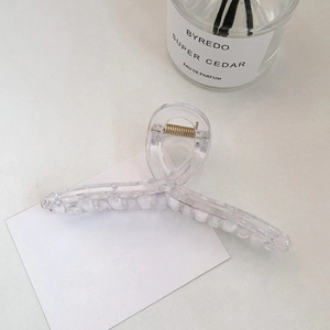 Detail of a large clear acrylic hair claw clip with golden spring and cross streamline design
