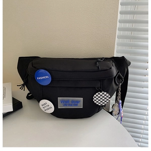 Detail of black nylon chest bag with fashion badges and astronaut keychain accessory