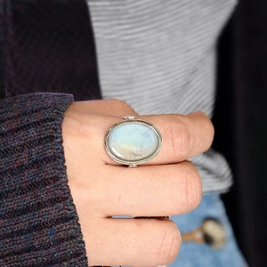 Close-up of vintage oval moonstone ring with a silver bezel setting worn on finger