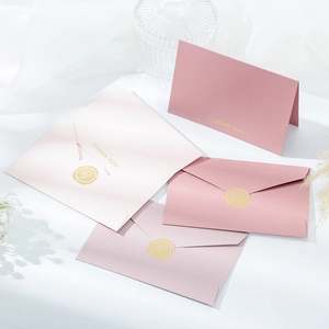 Detail of pink envelopes with gold foil THANK YOU lettering and wax seal accents