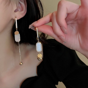 Detail of emerald green leaf tassel earrings with asymmetric golden dangle fringe
