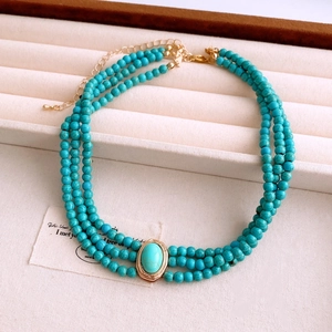Vue détaillée du collier multicouche en perles vertes avec pendentif ovale doré