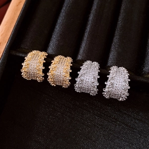 Detail of gold and silver C-shaped huggie earrings with pavé set zircon stones