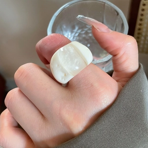 Detail of minimalist creamy resin ring with mother of pearl inlay on woman finger