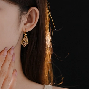 Close-up of gold diamond rhombus leaf earrings with champagne stones on model
