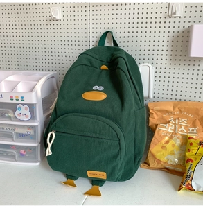 Detail of green corduroy backpack featuring a cute 3D cartoon duck design for students