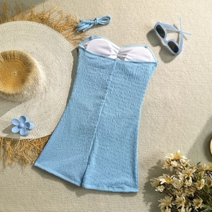 Flat lay of light blue smocked one-piece swimsuit with beach accessories and matching headband