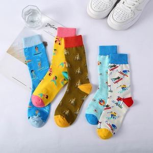 Colorful mid-calf cotton socks with sports motifs and white sneakers on a clean background