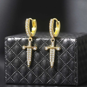 Detailed view of gold-plated dagger earrings paved with white cubic zirconia on a box