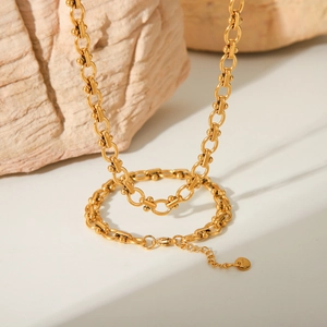 Industrial style gold stainless steel link chain necklace on textured stone background