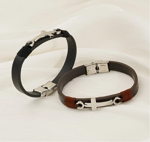 Détail macro de bracelets en cuir avec croix en acier sur fond de soie blanche