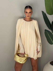 Détail d'une élégante robe beige style cape avec tissu plissé et coupe ample décontractée