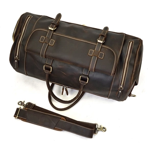 Detail of vintage brown leather travel bag showing adjustable shoulder strap and hardware