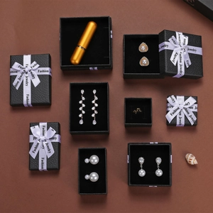 Detail view of high-end black jewelry gift box with assorted pearl earrings and gold rings